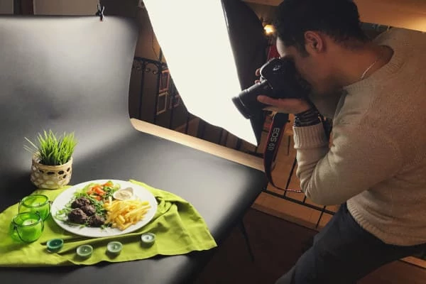 Vista lateral do fotógrafo masculino fotografando comida no pano de fundo