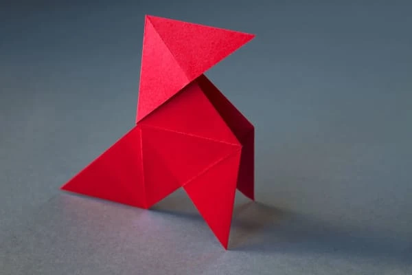 Origami de galinha de papel vermelho isolado em um fundo cinza