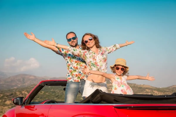 Família feliz viaja de carro nas montanhas Pessoas se divertindo em cabriolet vermelho Conceito de férias de verão