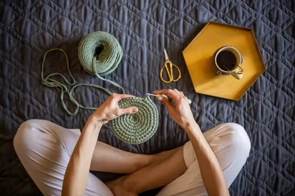 Seção baixa de mulher fazendo crochê em casa