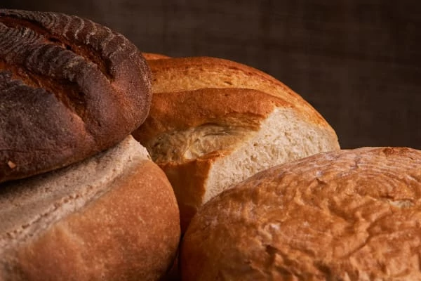 Pão e trigo diferentes na mesa rústica. Foco seletivo