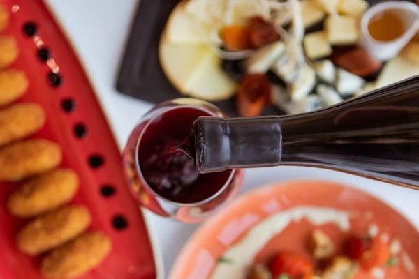 O vinho é derramado de uma garrafa em um copo no fundo de uma mesa com comida